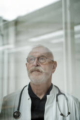 Nachdenklicher Arzt mit Schnurrbart und Brille in einer medizinischen Klinik - JOSEF07350