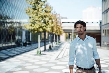 Handsome businessman with tablet PC standing at office park - GUSF07140