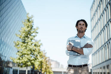 Businessman standing with arms crossed at office park - GUSF07141