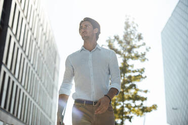 Businessman with tablet PC walking at office park on sunny day - GUSF07144