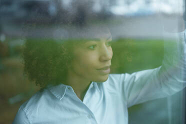 Contemplative businesswoman seen through glass of office - JOSEF07364