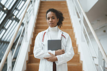Confident doctor with tablet PC in front of steps at hospital - JOSEF07420