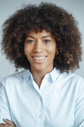 Smiling businesswoman with curly hair in office - JOSEF07421