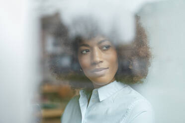 Businesswoman with brown curly hair seen through glass - JOSEF07457