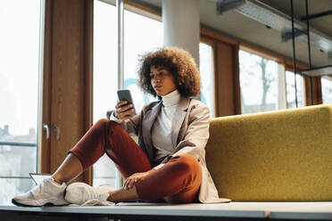 Businesswoman text messaging on mobile phone at work place - JOSEF07497