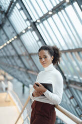 Businesswoman with tablet PC in corridor at office - JOSEF07521