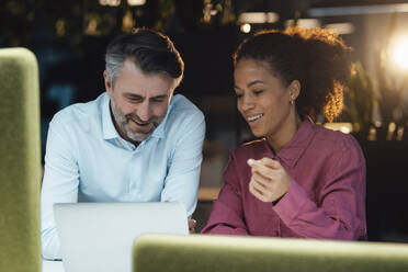 Happy businessman colleagues discussing over laptop in office - JOSEF07543