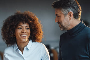 Businessman discussing with happy colleague at work place - JOSEF07552