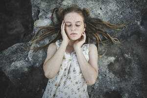 Junge Frau mit Dreadlocks auf einem Felsen liegend - TETF00761