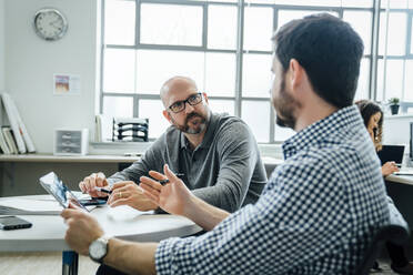 Männer benutzen ein digitales Tablet während einer Besprechung im Büro - TETF00866