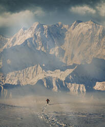 Man hiking through snow by mountain in Alpe Devero, Italy - TETF00954