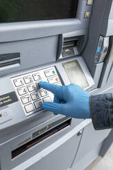 Close-up of gloved hand on keypad of ATM machine - TETF00963