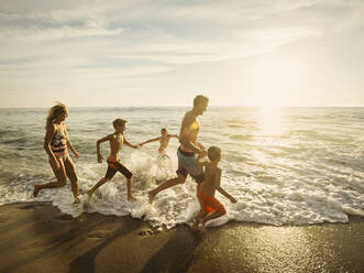 Familie mit drei Kindern (6-7, 10-11, 14-15) beim Laufen am Strand - TETF01010