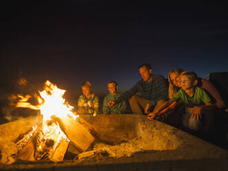 Familie mit drei Kindern (6-7, 10-11, 14-15) beim Kochen von Marshmallows - TETF01013