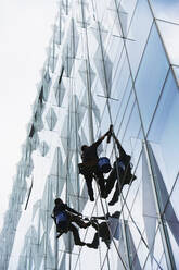 USA, New York, New York City, Fensterputzer reinigen Glasfassade eines Bürogebäudes - TETF01204