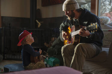Junge (4-5) hört seinem Vater beim Gitarrenspiel zu - TETF01219