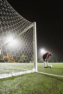 USA, California, Ladera Ranch, goalie on illuminated soccer field at night - TETF01232