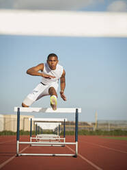 Boy (12-13) hurdling on running track - TETF01240