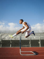 Boy (12-13) hurdling on running track - TETF01241