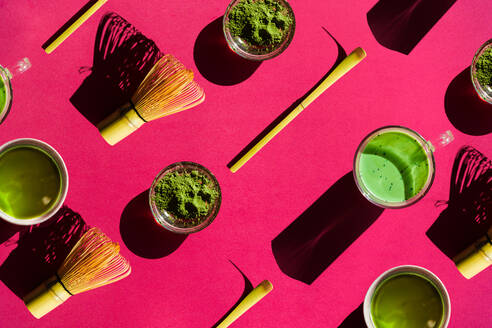 Ansicht von oben Vollbild hellen Hintergrund des Glases von grünem Tee und getrockneten Matcha mit Bambus chasen und chashaku auf rosa Oberfläche - ADSF33793