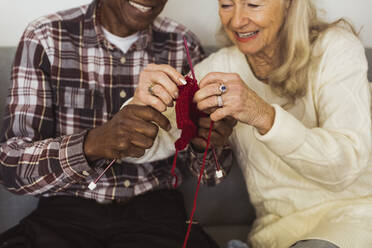 Elderly man and woman knitting together at retirement home - MASF28977