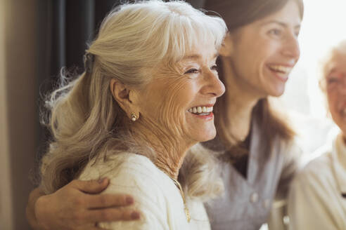 Happy elderly woman by female caregiver at nursing home - MASF28978