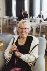 Porträt einer lächelnden älteren Frau, die im Pflegeheim strickt - MASF28981