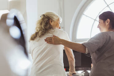 Female caregiver talking with elderly woman exercising on treadmill at retirement home - MASF28998