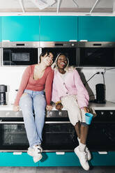 Glückliche junge Frauen sitzen am Küchentisch im Studentenwohnheim - MASF29036