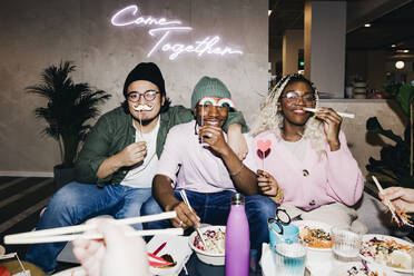 Portrait of happy multiracial male and female friends with props having food in college dorm - MASF29041