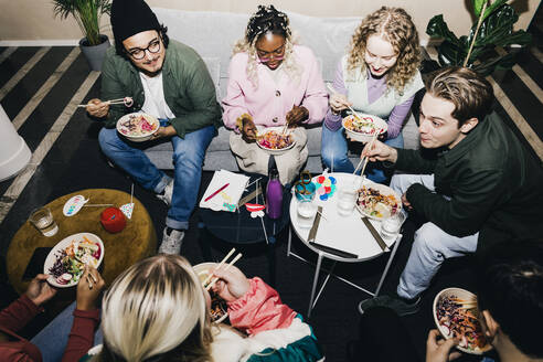 Blick von oben auf männliche und weibliche Studenten verschiedener Rassen, die im Studentenwohnheim Essen genießen - MASF29043