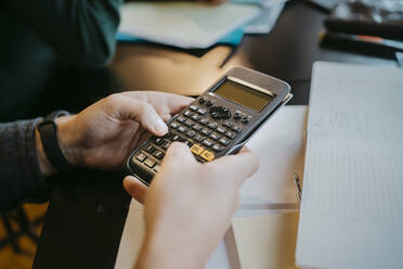 Hands of young male student using calculator at university - MASF29072