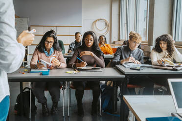 Multirassische Schüler sitzen am Schreibtisch und lernen vom Lehrer im Klassenzimmer - MASF29105