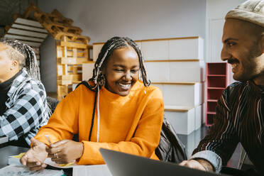 Cheerful man and woman sharing laptop in classroom of community college - MASF29133