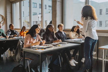 Professor explaining multiracial university students sitting in classroom - MASF29138