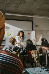 Smiling professor teaching students in classroom at university - MASF29140