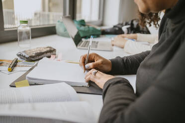 Mittelteil einer reifen Studentin, die während ihres Studiums in ein Buch schreibt - MASF29157