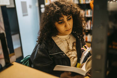 Junge Studentin liest ein Buch in der Hochschulbibliothek - MASF29221