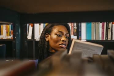 Junge Frau sucht ein Buch in der Bibliothek der Universität - MASF29227