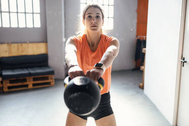 Junge Frau mit Kettlebells beim Training im Fitnessstudio - JSRF01937