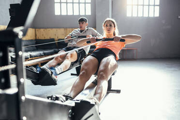 Junge Frau und Mann trainieren mit einem elastischen Seil im Fitnessstudio - JSRF01940