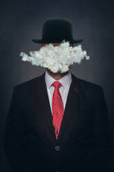 Cloud covering face of man wearing hat against black background - VTF00660