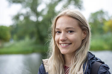 Glückliche junge Frau mit blondem Haar im Park - BFRF02411