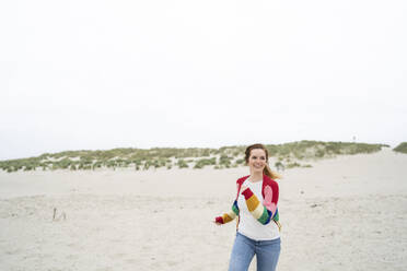 Glückliche junge Frau läuft auf Sand - AKLF00546