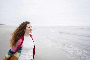 Lächelnde rothaarige Frau, die das Wochenende am Strand genießt - AKLF00565