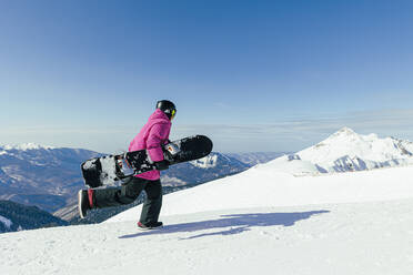 Man with snowboard running on snowy mountain - OMIF00735