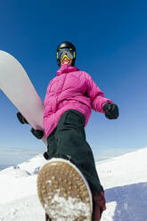 Glücklicher Mann mit Snowboard an einem sonnigen Tag - OMIF00742