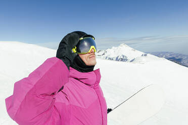 Snowboarder adjusting helmet on sunny day - OMIF00748