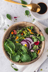 Top view of wooden bowl with tasty salad with sprouts and vegetables placed on table for healthy lunch - ADSF33926