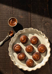 Von oben gesalzenes Karamell-Schokoladengebäck auf Keramikteller auf Holztisch Hintergrund - ADSF33947